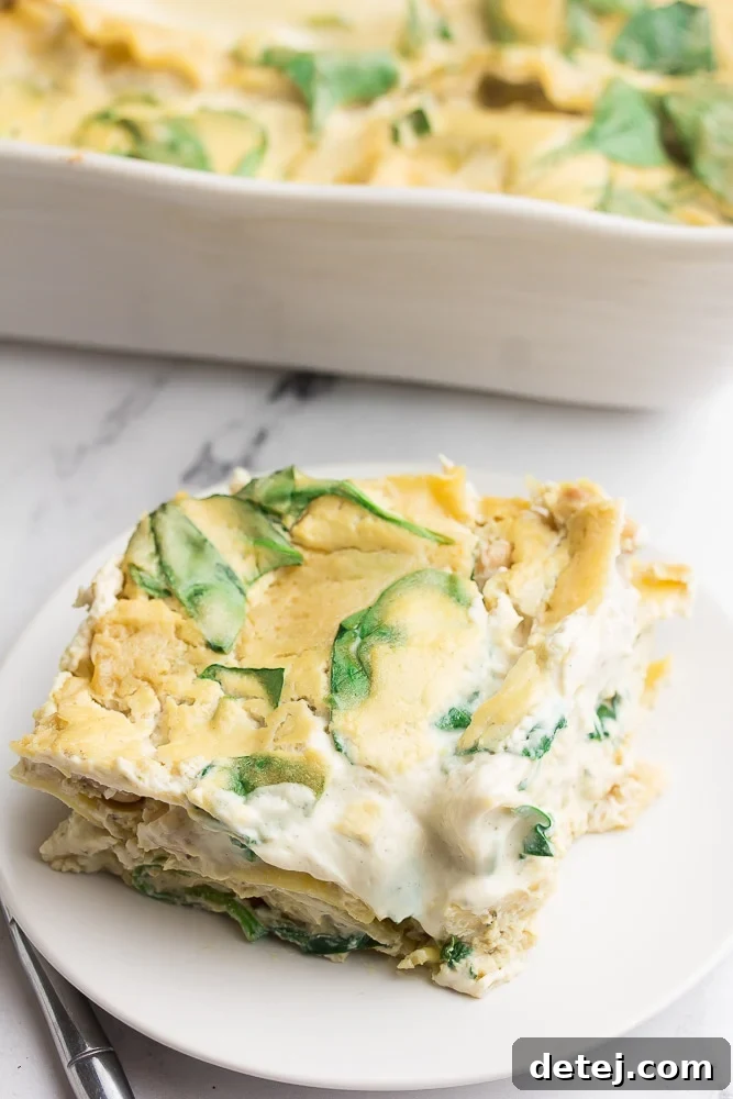 A generous slice of creamy Vegan White Lasagna on a white plate, set against a elegant marble background, showcasing its delicious layers.