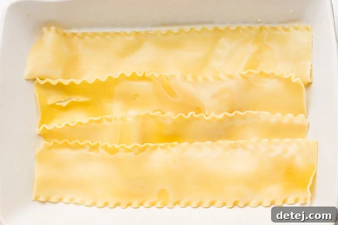 Cooked lasagna noodles are carefully arranged to form the first layer in the casserole dish for the Vegan White Lasagna.