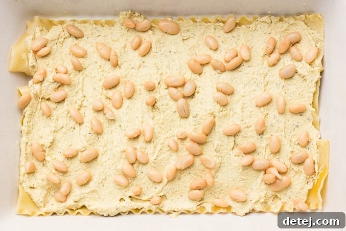 Hearty white beans are generously sprinkled over a layer of vegan ricotta in the lasagna, adding texture and protein to the Vegan White Lasagna.
