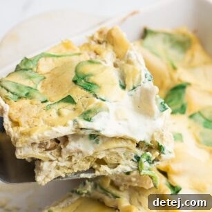 A close-up image of a perfectly baked piece of Vegan White Lasagna being served from a casserole dish, highlighting its golden crust and creamy interior.