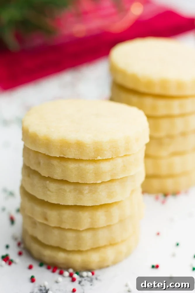 Stacks of golden vegan shortbread cookies with a festive red towel, highlighting their perfect texture.