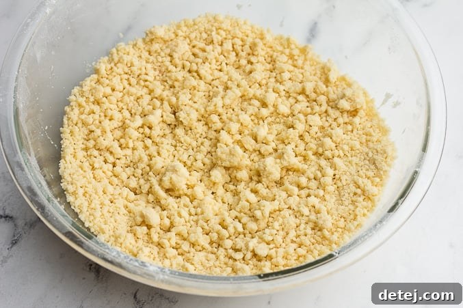 Close-up of mixed crumbly vegan cookie dough in a bowl, showing its readiness for shaping.
