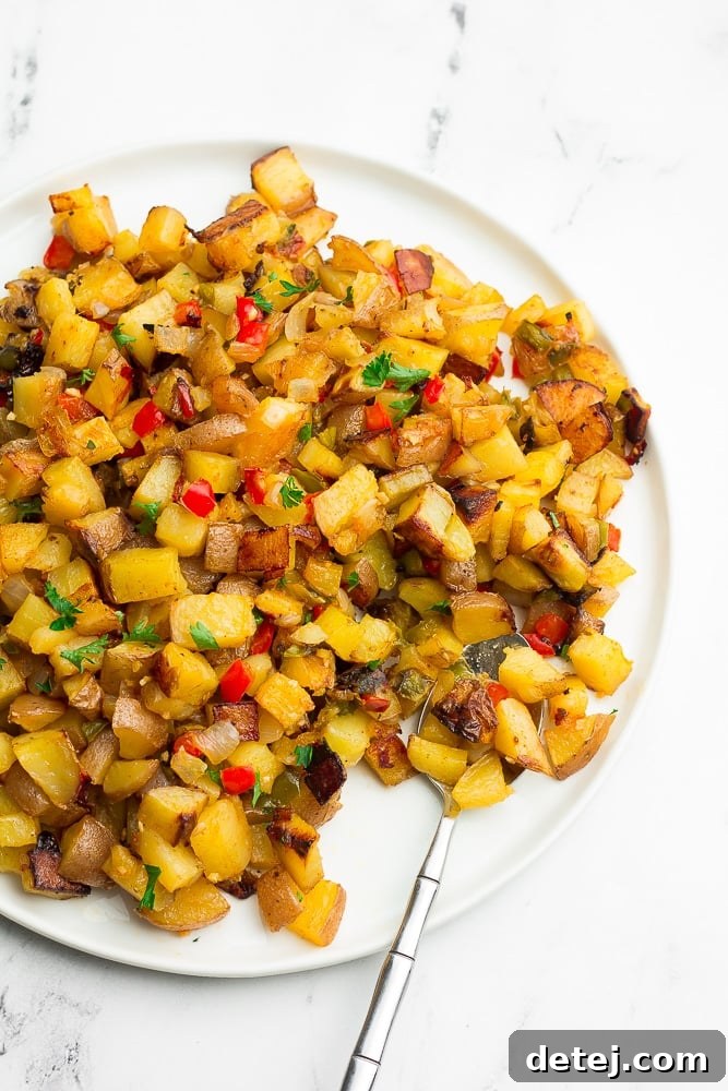 A vibrant plate filled with perfectly crispy oven roasted breakfast potatoes, garnished with fresh parsley, ready to be enjoyed as a hearty breakfast or brunch side.