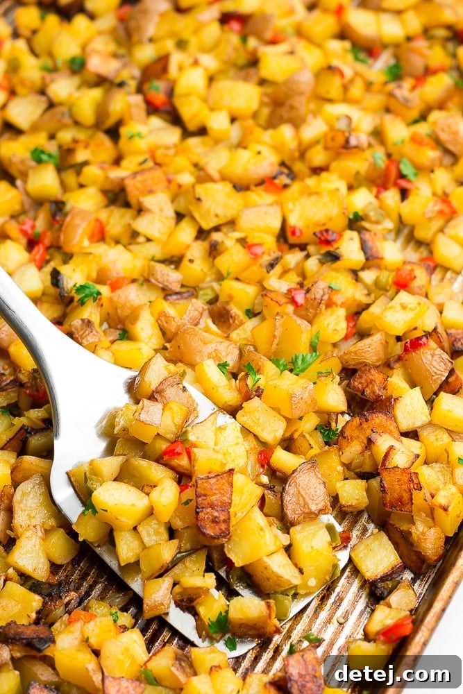 A close-up shot of a metal spatula lifting perfectly golden-brown and crispy oven roasted breakfast potatoes from a baking sheet, showcasing their delicious texture and preventing sticking.