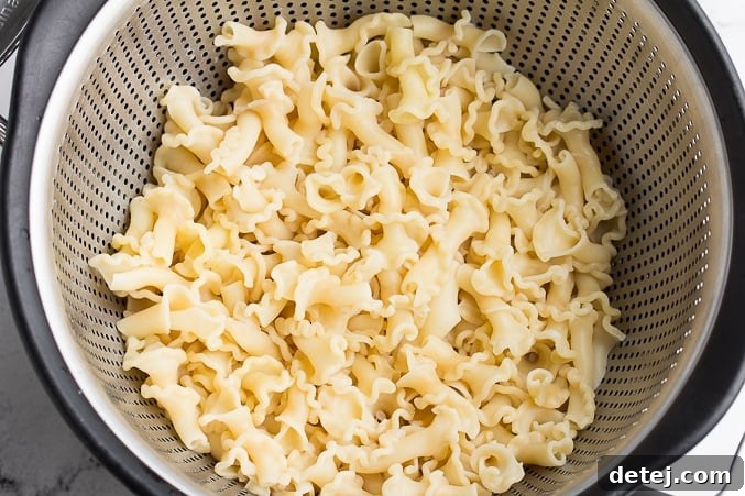 Perfectly cooked, drained noodles resting in a colander, ready to be added to the warm, flavorful vegan chicken noodle soup.