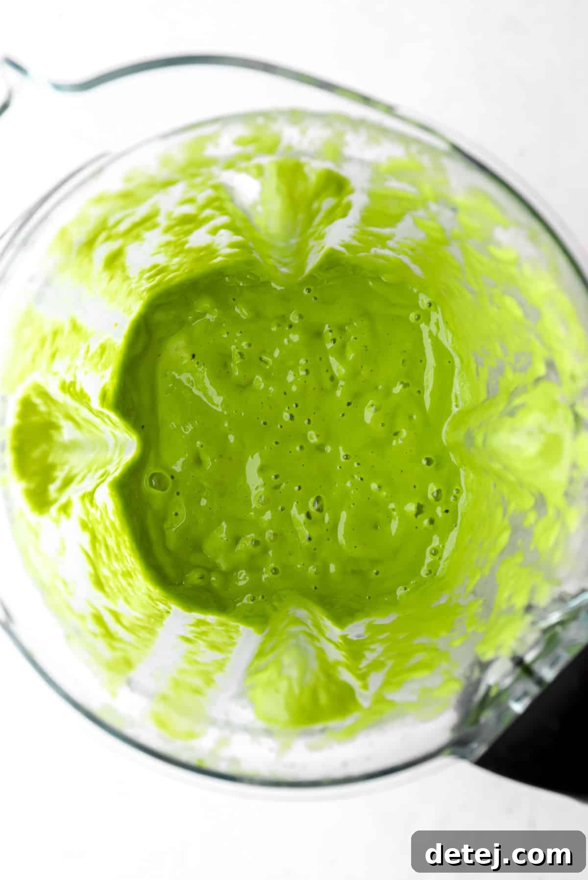 A high-powered blender showcasing a perfectly blended, smooth green kale smoothie, ready to be poured and enjoyed.
