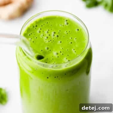 square image of a kale smoothie in a glass with a straw