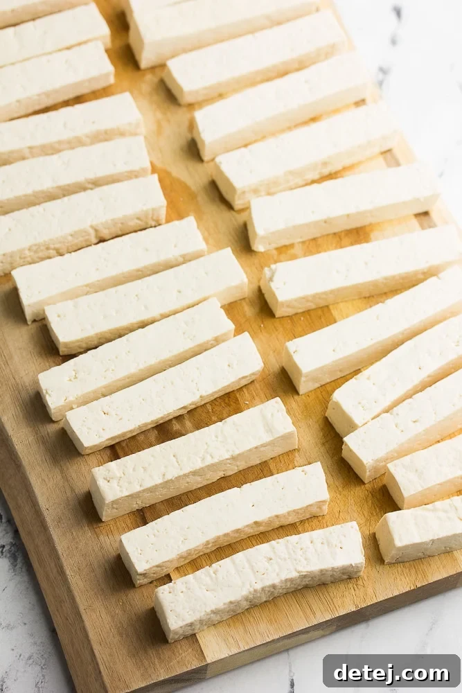 Firm tofu sliced into uniform rectangular sticks, ready for coating.