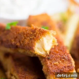A perfectly golden-brown fried tofu fish stick with a bite taken out, showing its tender interior.