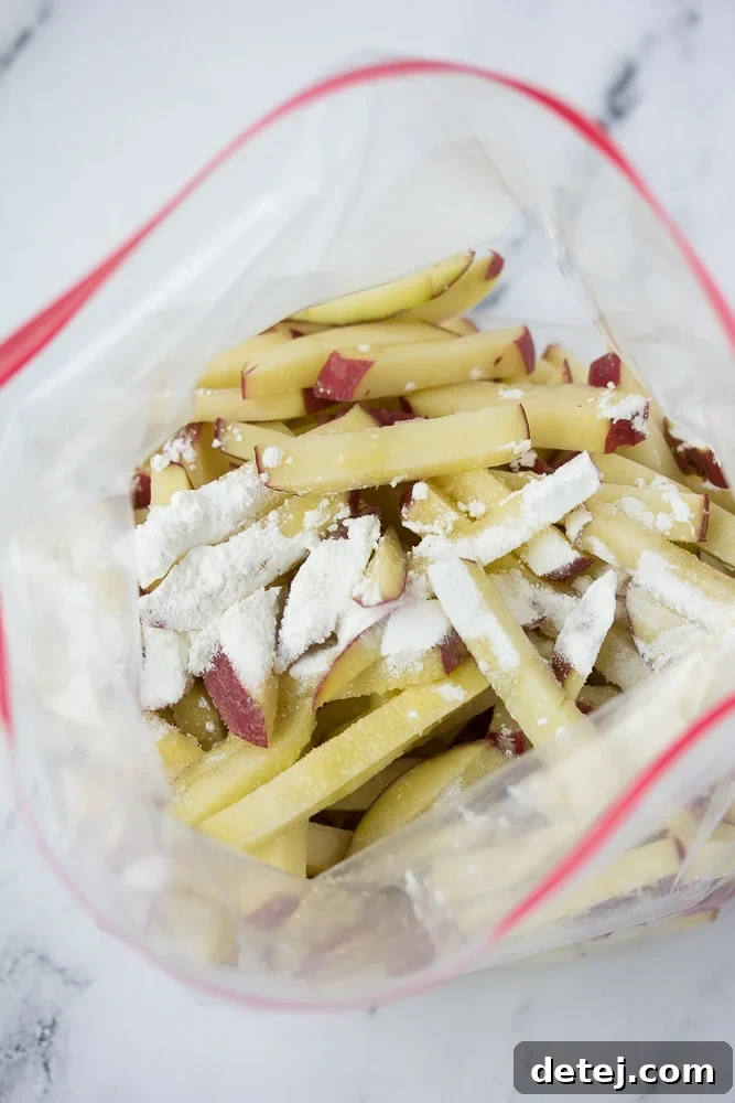 Sliced potatoes in a plastic bag with olive oil, cornstarch, and spices, ready for mixing.