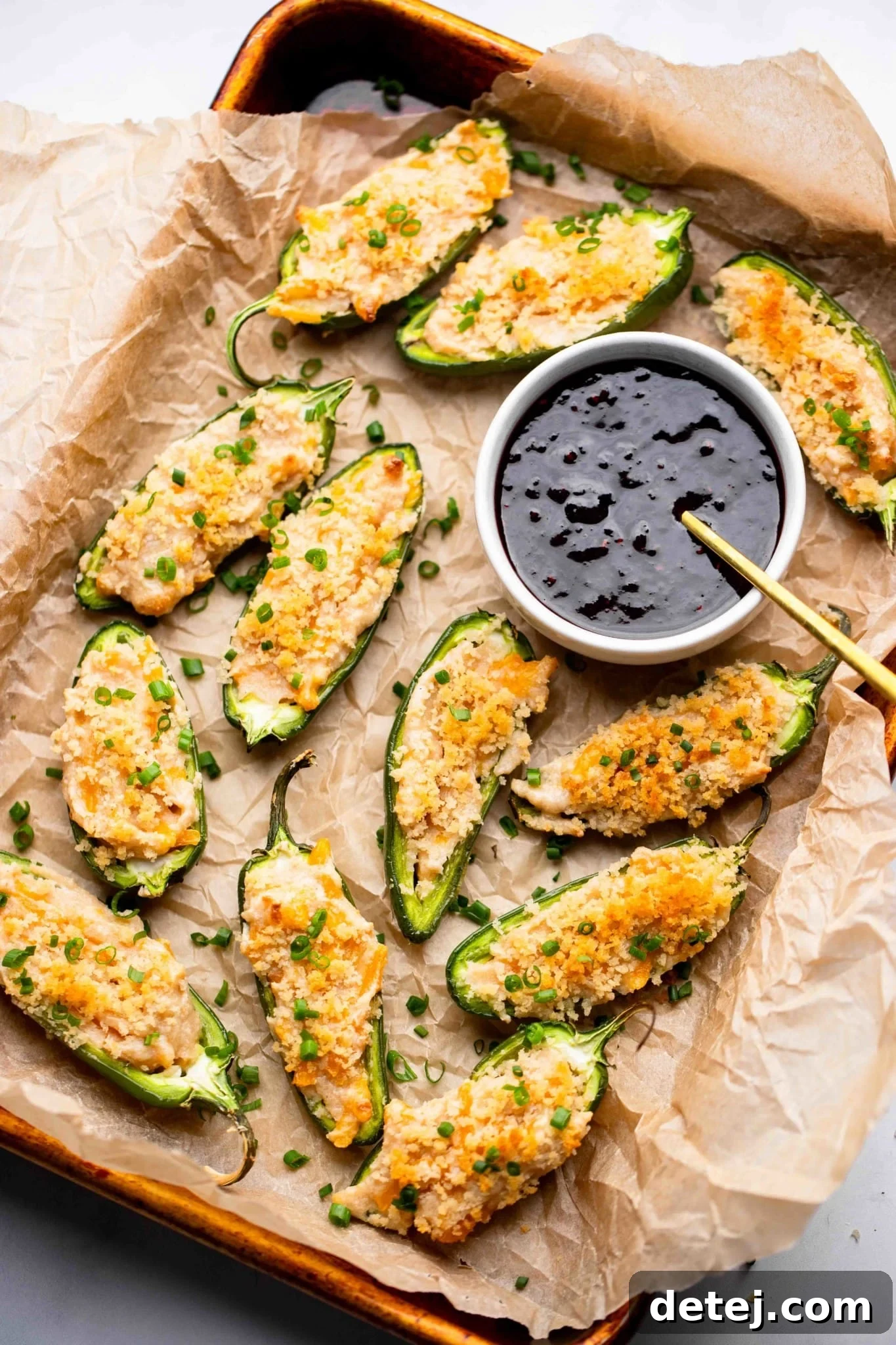 Vegan Jalapeno Poppers on a tray next to a small bowl of raspberry sauce.