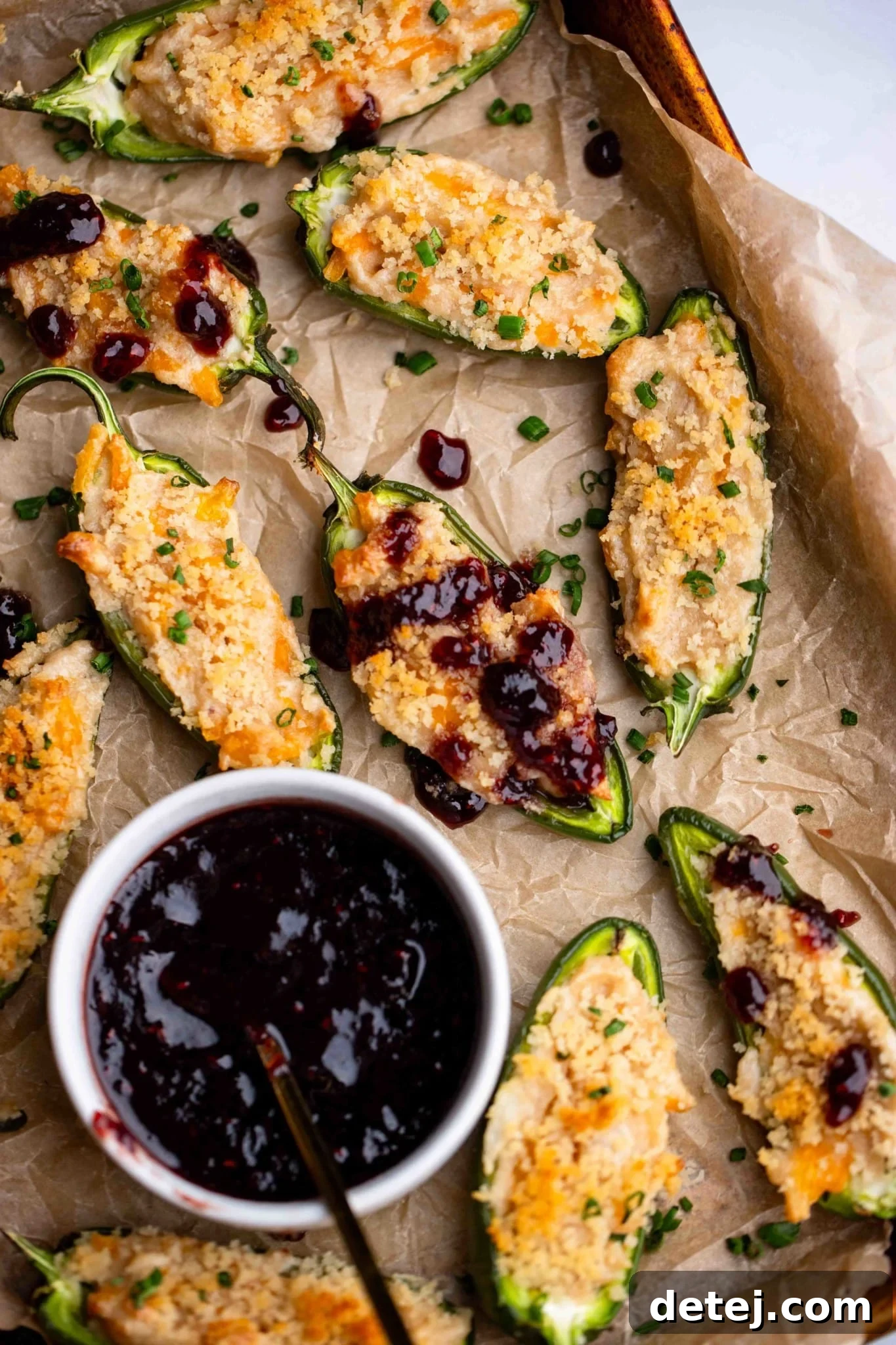 Vegan Jalapeno Poppers on a tray next to a small bowl of raspberry sauce.