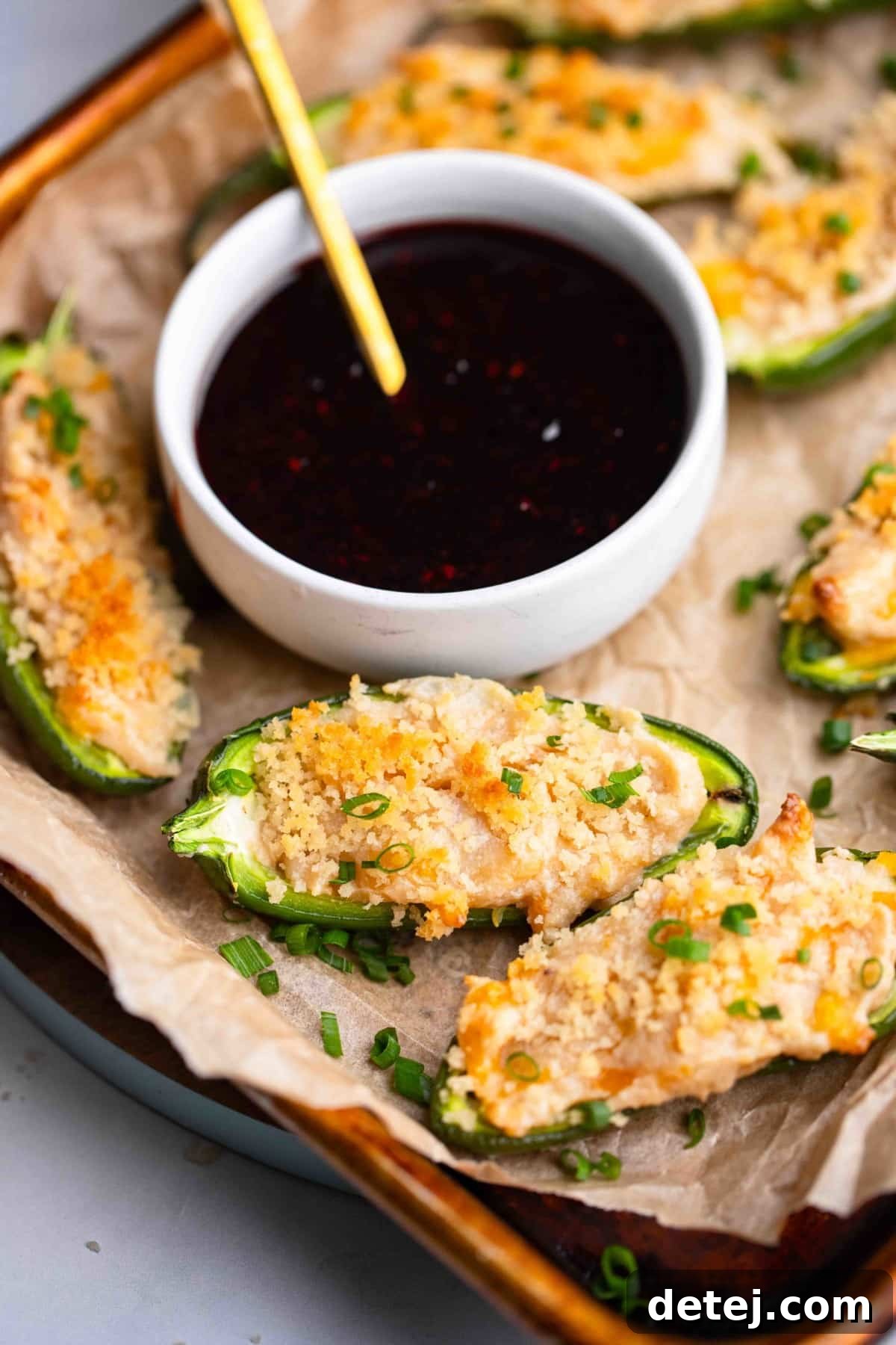 close up on Vegan Jalapeno Poppers on a tray next to a bowl of raspberry sauce.