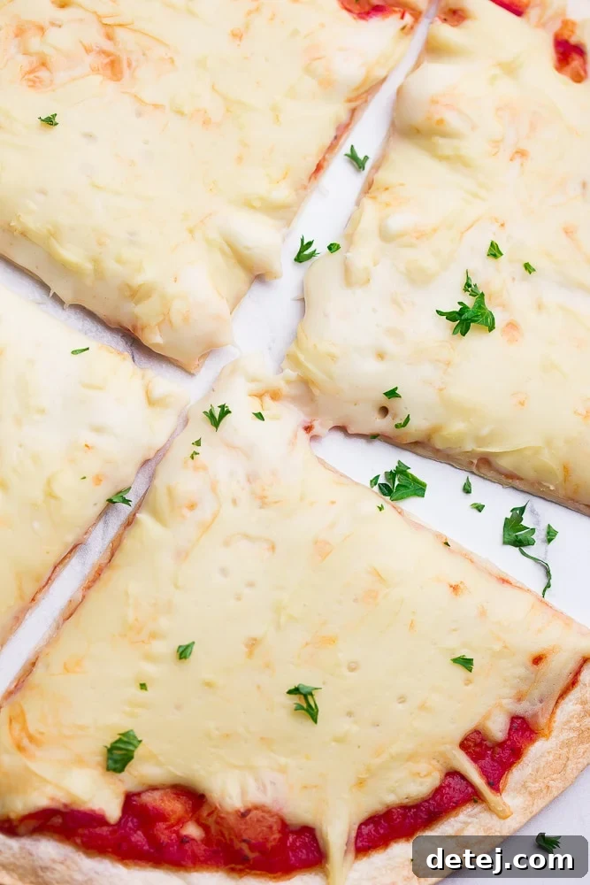 A close-up shot of a sliced pizza, showing melted vegan mozzarella and a sprinkle of fresh parsley, emphasizing its appetizing appeal.