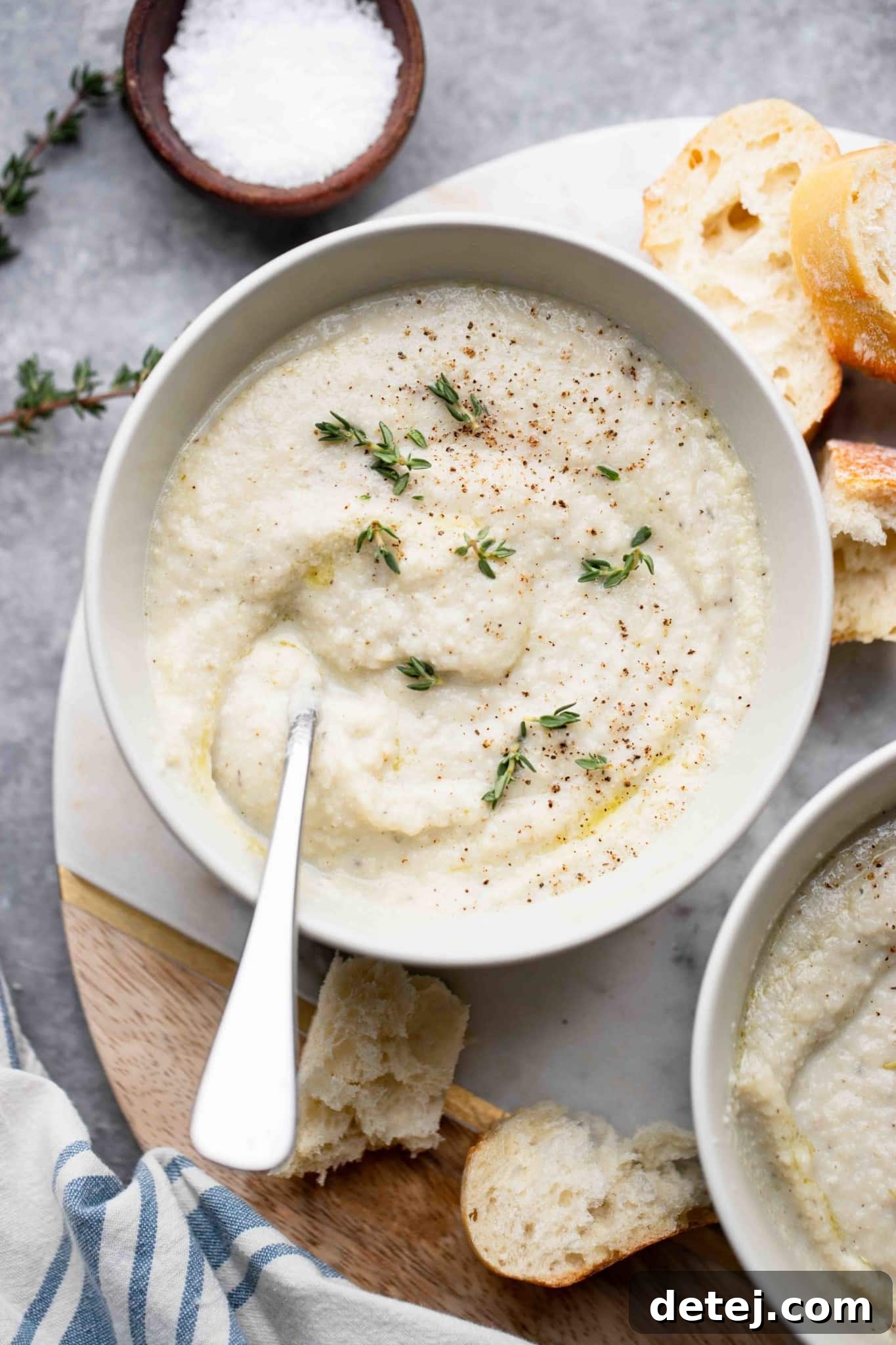 A beautifully presented bowl of creamy vegan cauliflower soup, garnished with fresh herbs and a drizzle of olive oil, ready to be enjoyed.
