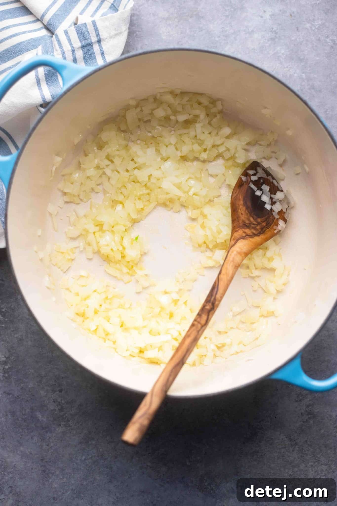 Chopped onions are sautéing in olive oil in a large pot, beginning the aromatic base for the vegan cauliflower soup.