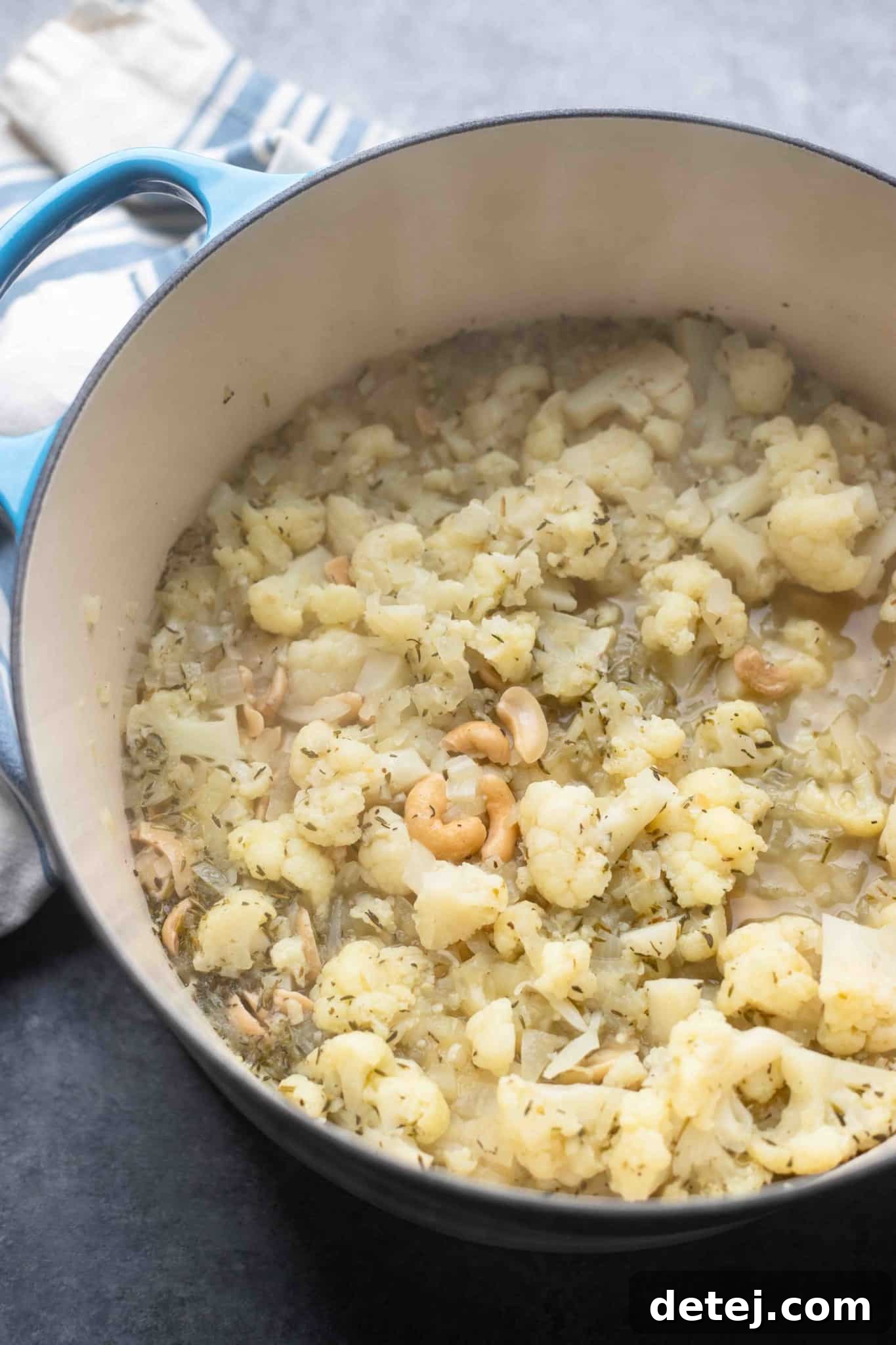 The cooked ingredients for vegan cauliflower soup, tender and ready for blending, resting in a large pot.