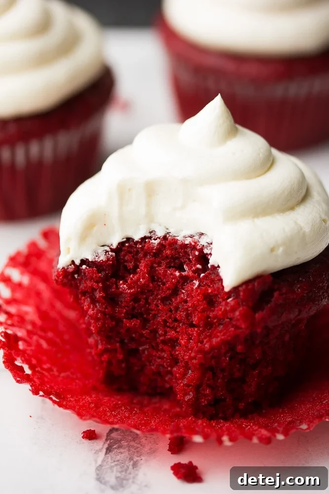 bite taken out of a vegan red velvet cupcake, revealing its moist and fluffy interior