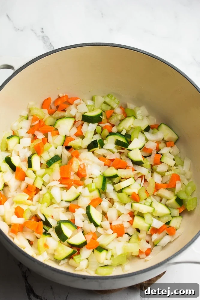 Fresh vegetables being sautéed in a large soup pot, building the flavorful base for minestrone.