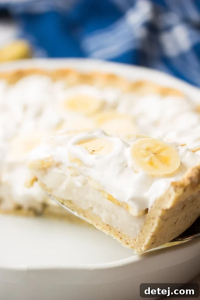 A slice of creamy Vegan Banana Cream Pie being carefully lifted out of the pie dish, revealing its perfect layers.