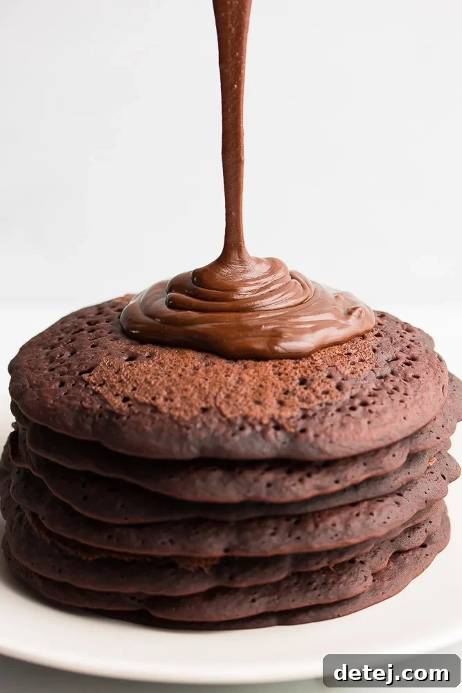 vegan ganache being poured onto chocolate pancakes, white background, showing its rich, glossy texture