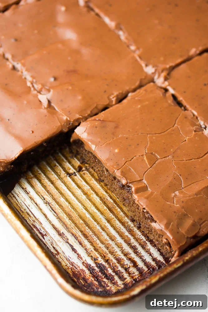 close up of pan of sheet cake with one slice removed, showcasing the rich frosting