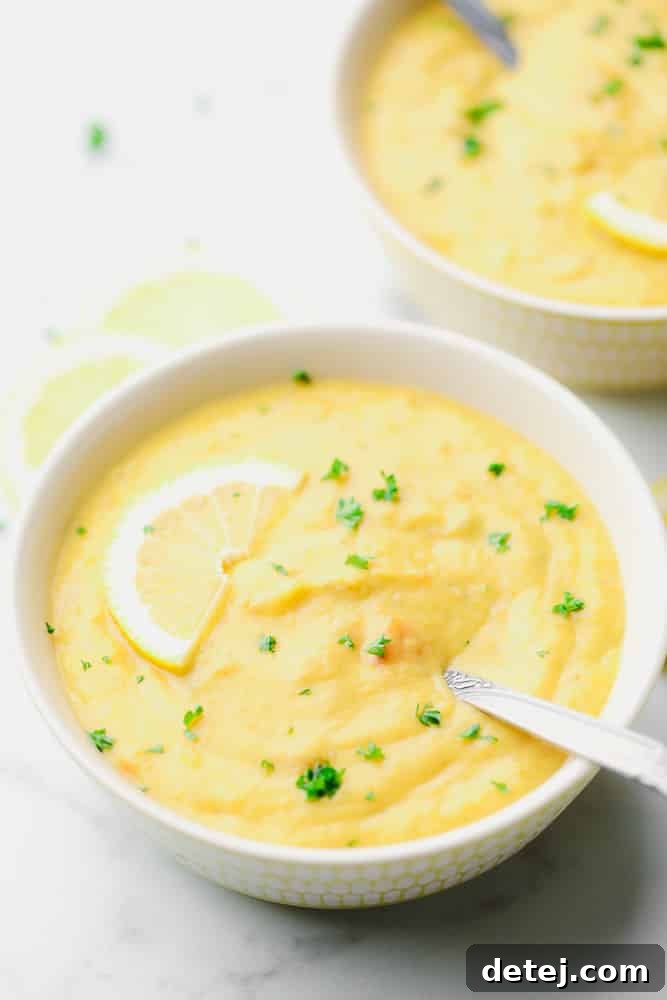 two bowls of yellow soup with a lemon slice on top and parsley