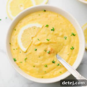 square image of a bowl of yellow soup with a spoon in it