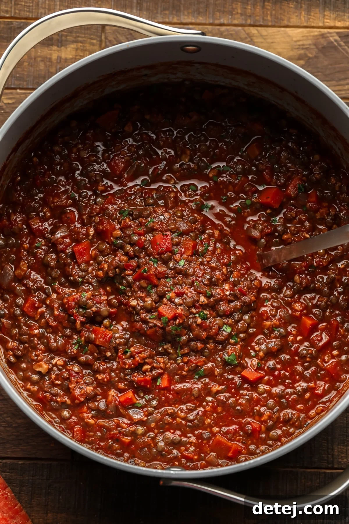 pot with rich red lentil bolognese sauce with a ladle