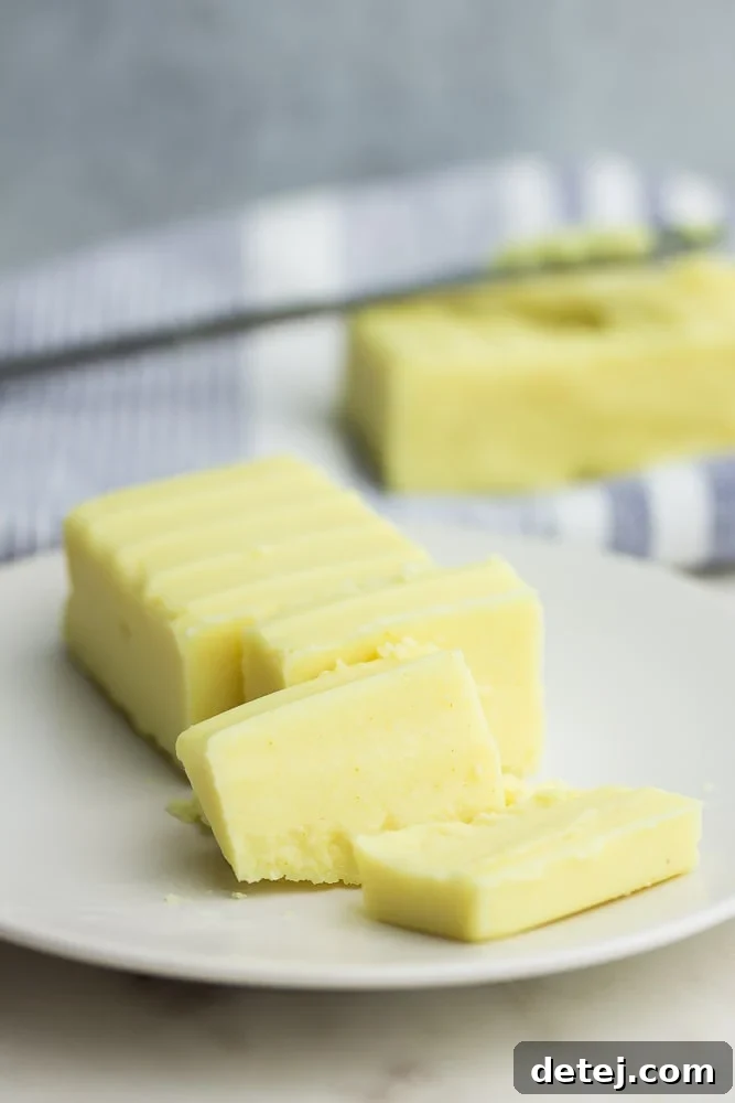 Freshly sliced homemade vegan butter on a plate with more butter in the background