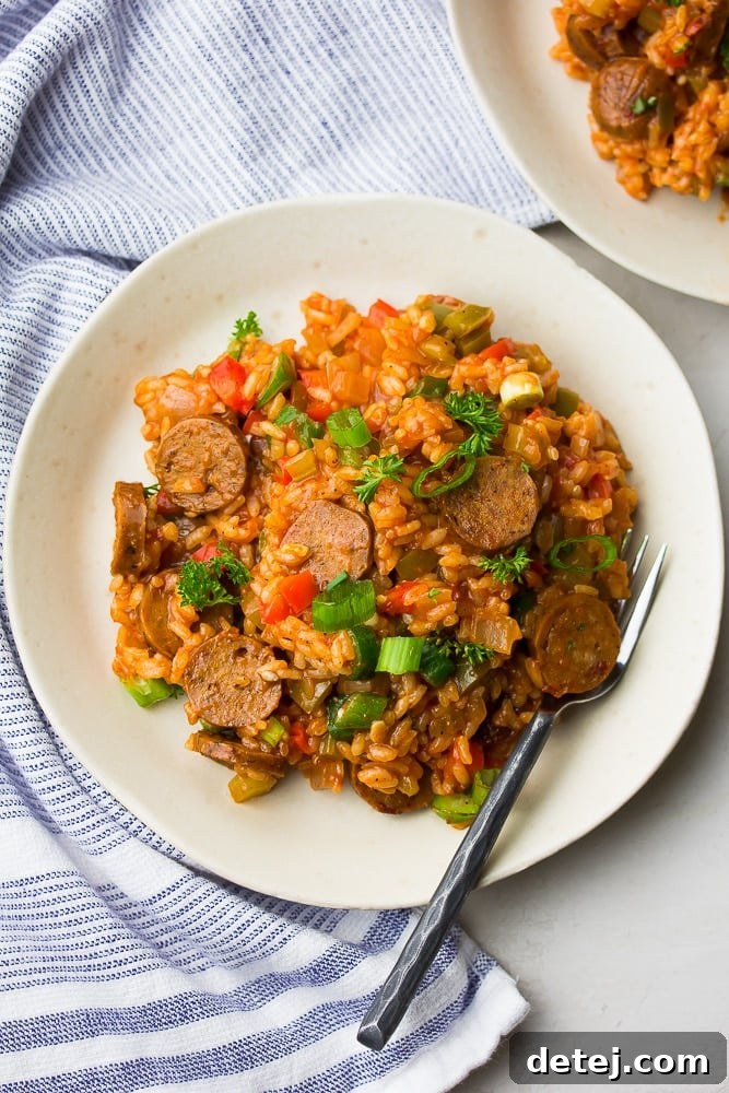 Southern Comfort, Vegan Style 3 White plate with a serving of vegan jambalaya, fork, and blue striped towel on a rustic wooden surface