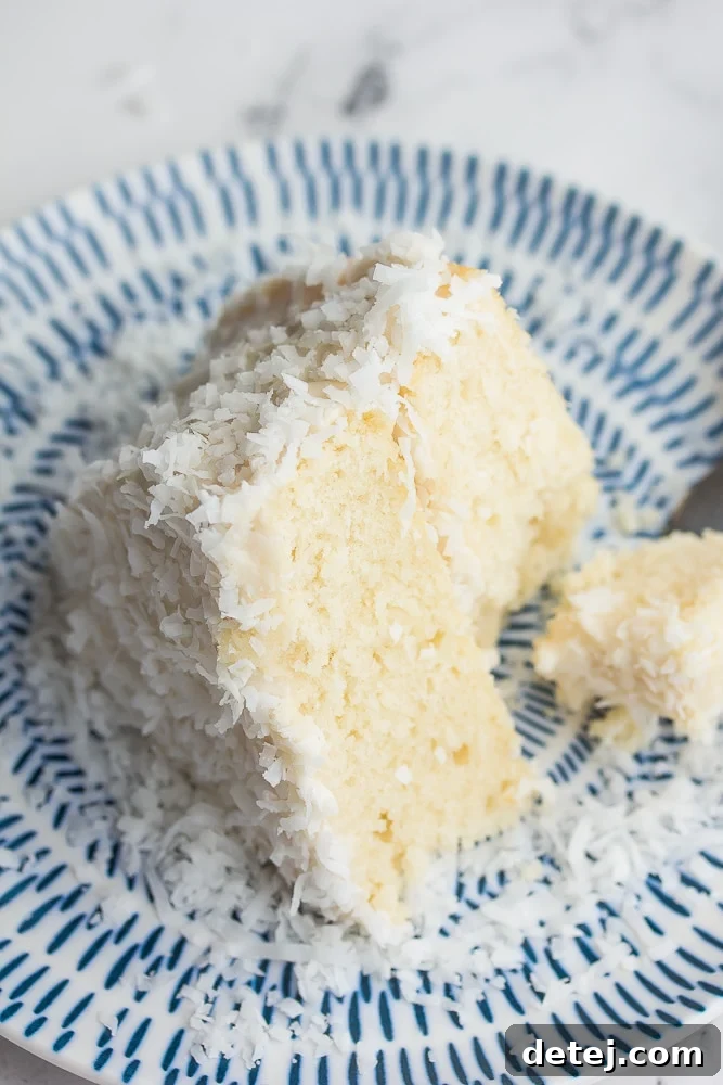 A delectable slice of vegan coconut cake, revealing its fluffy layers and creamy frosting, with a gentle bite taken to showcase its inviting texture. Ideal for plant-based dessert lovers.