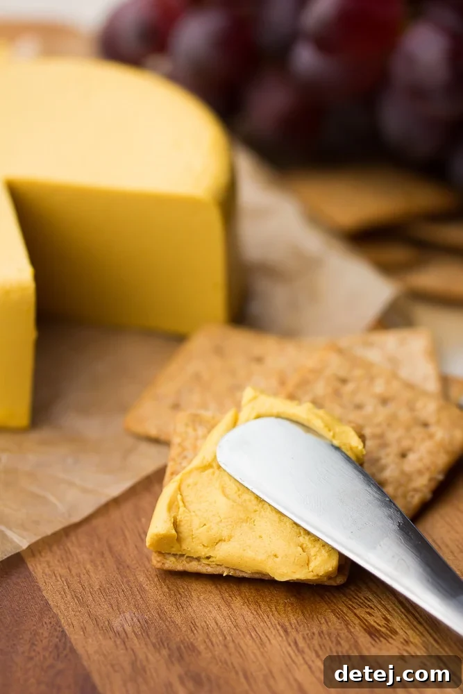 spreading homemade vegan cheddar cheese on a cracker