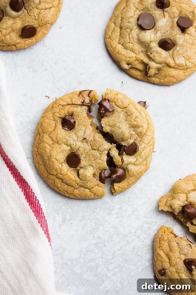 A single, perfectly baked chocolate chip cookie resting on a rustic kitchen towel, highlighting its golden edges and generous chocolate chunks.