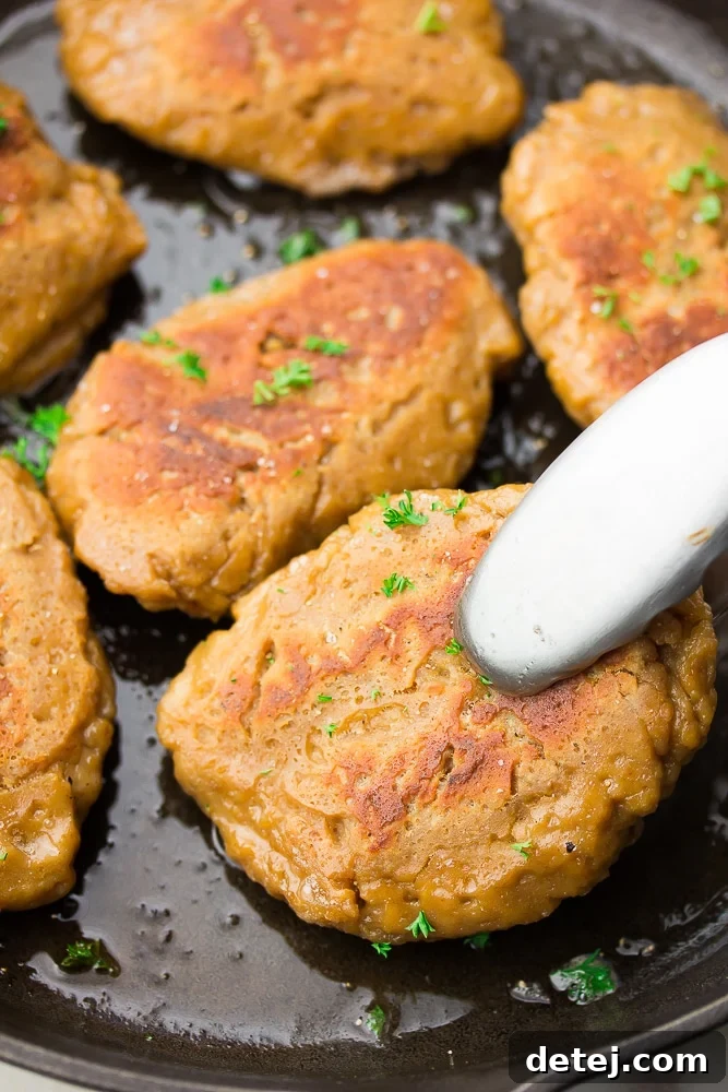 Plant-Based Chicken 2 A perfectly seared piece of vegan chicken being picked up with tongs from a hot skillet, showcasing its delicious, golden-brown exterior and inviting texture.
