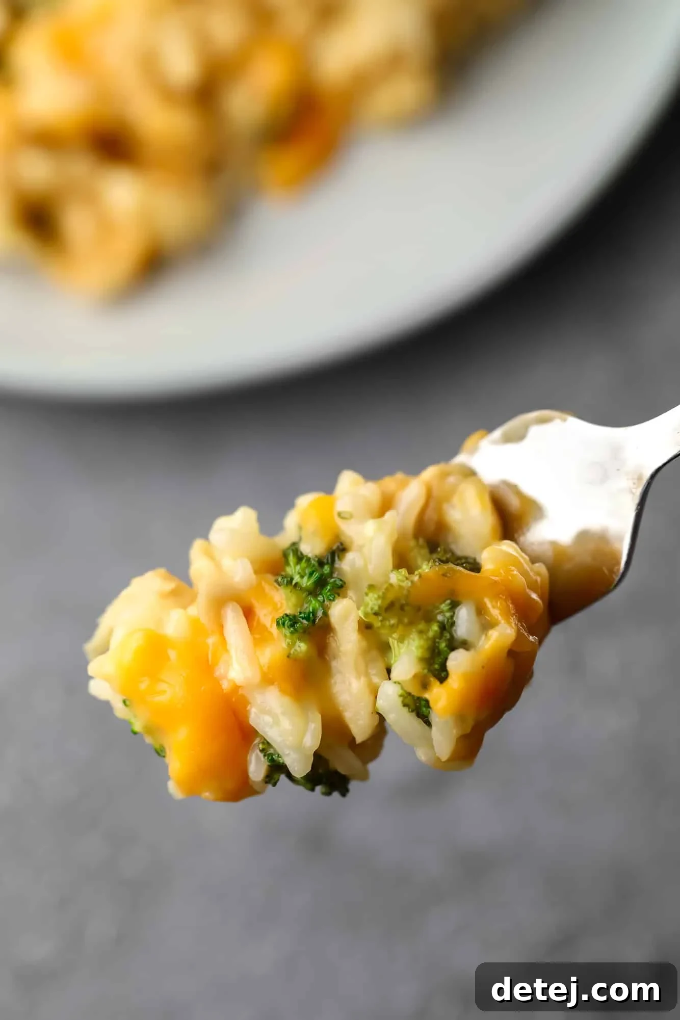 Close-up of a forkful of vegan chicken, broccoli, and rice casserole, showing the cheesy coating and texture.