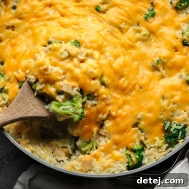 a wooden spoon in a cheese-covered broccoli and rice vegan casserole.