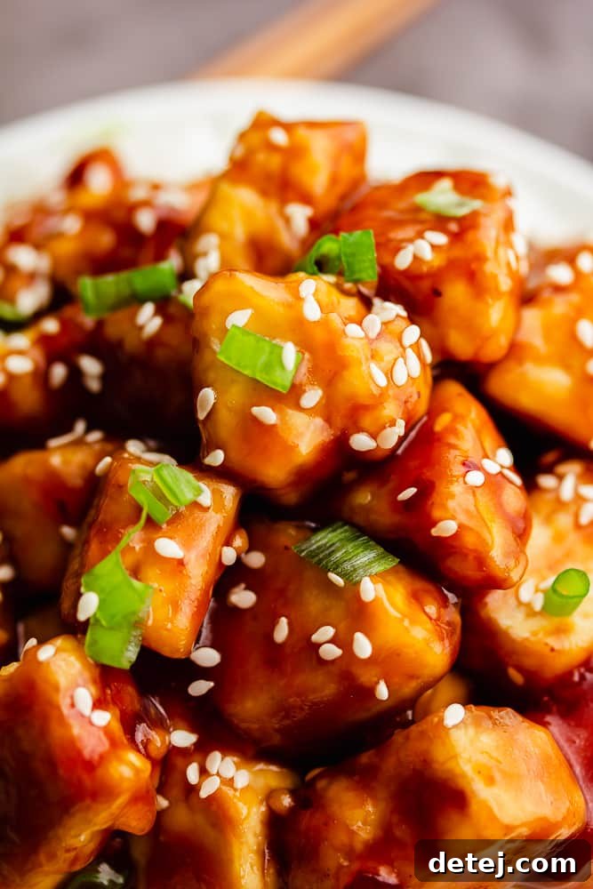 Close-up of General Tso's Tofu with chopped green onions and sesame seeds, showcasing the sticky sauce.