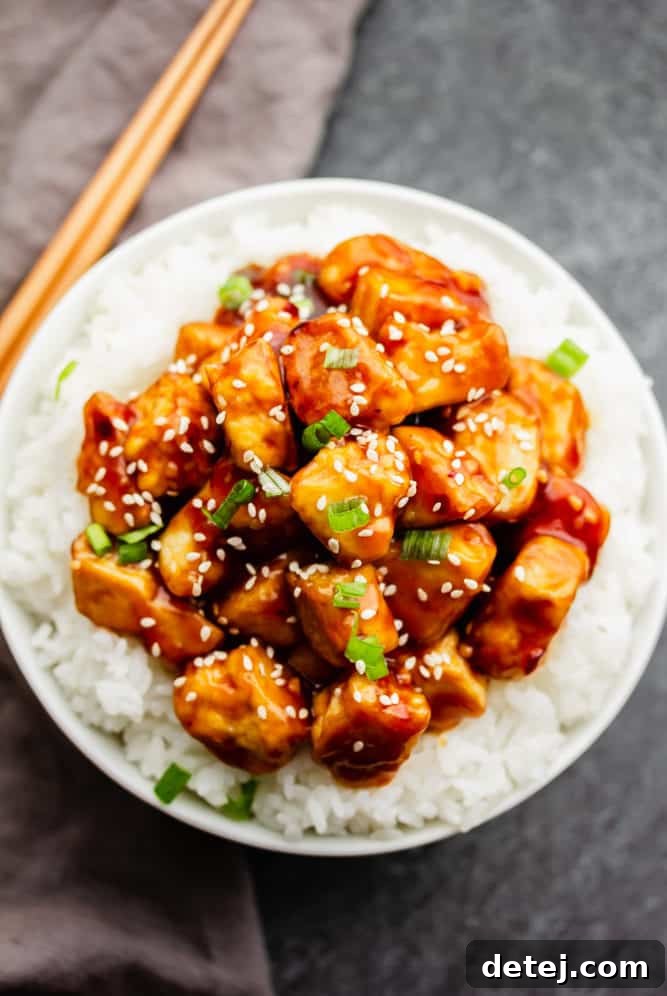Bowl with white rice and a generous portion of General Tso's Tofu in sauce, garnished.