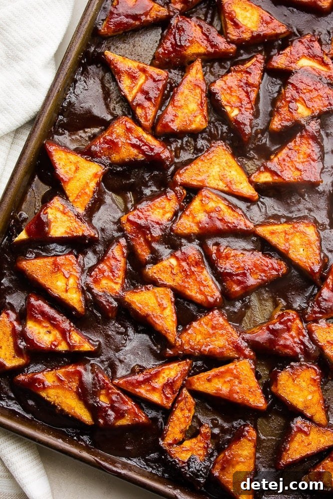 Golden brown crispy tofu pieces coated in BBQ sauce on a baking sheet, ready to be served.