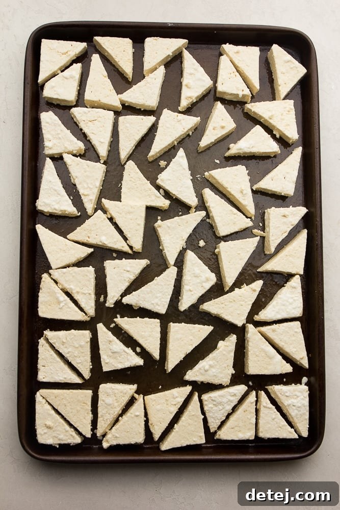 Triangle-shaped tofu pieces arranged neatly on a lightly oiled baking sheet, before being covered in BBQ sauce.