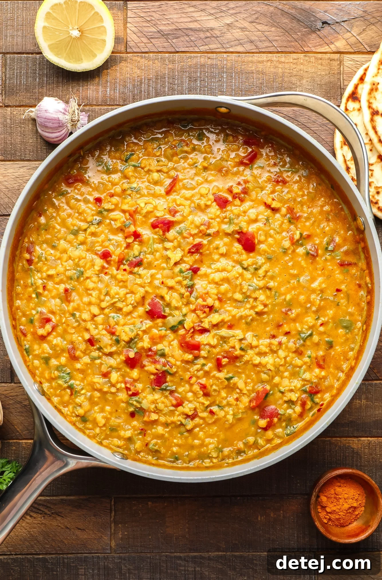 A cooked batch of creamy red lentil dahl simmering in a large grey pot, ready to be served.
