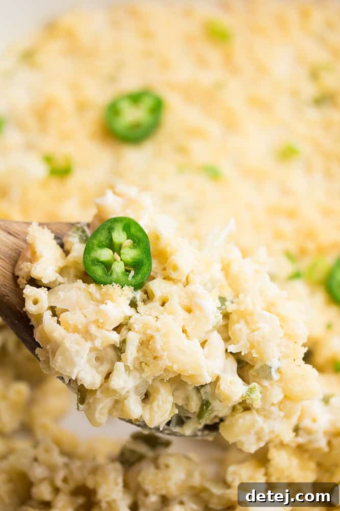 spoonful of mac and cheese with a jalapeño slice from casserole dish