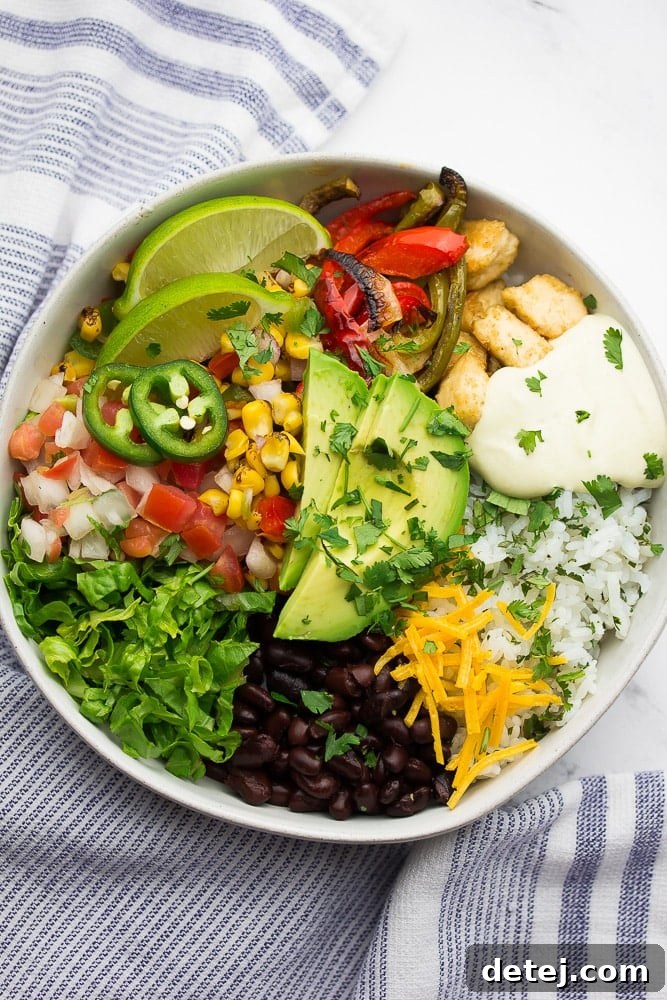 A beautifully arranged vegan burrito bowl with cilantro lime rice, black beans, vegan queso, avocado slices, and crispy tofu chik'n.