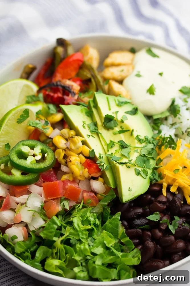 A close-up shot of a generously filled vegan burrito bowl, topped with creamy avocado slices and fresh cilantro, showcasing its vibrant layers.
