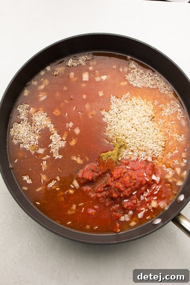 rice, tomatoes, broth, and spices in a pan before mixing