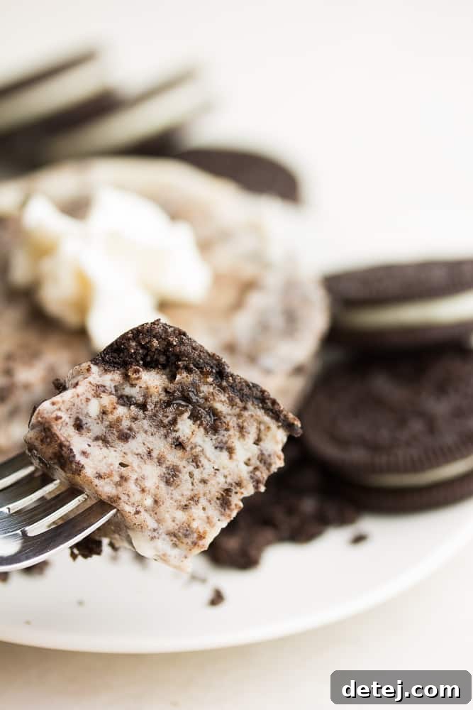 A fork taking a delicious bite out of the vegan Oreo mug cheesecake, showcasing its creamy texture and cookie pieces.