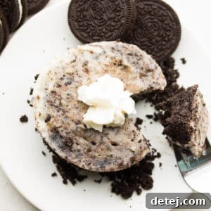 Square image of a small cheesecake with Oreos and whipped cream on top, ready to be served.