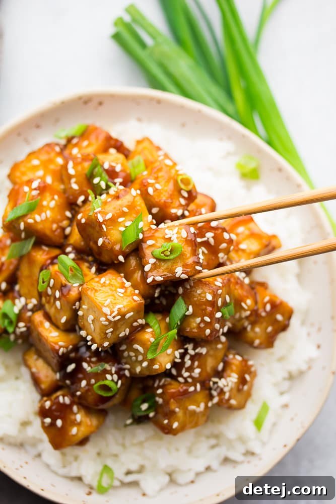 chopsticks grabbing crispy sesame tofu from a bowl