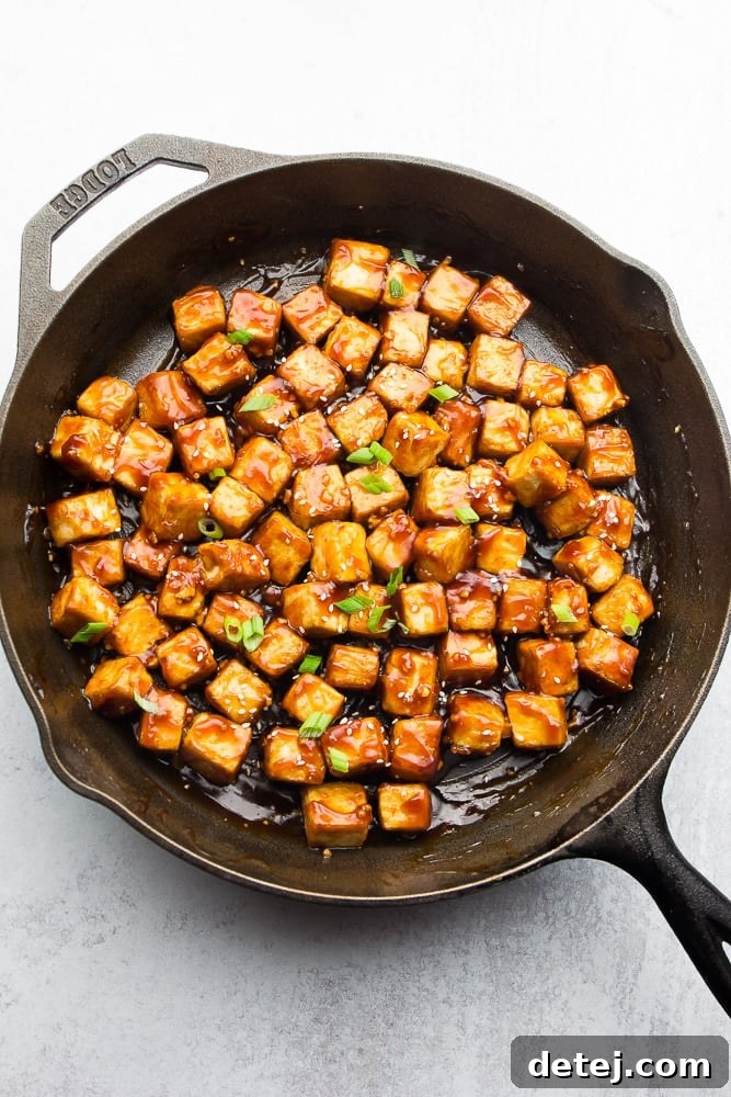 cast iron pan full of sesame tofu in sauce, garnished